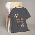 Dark gray t-shirt with 'Spring Into Gardening' text and flowers on a wooden chair.