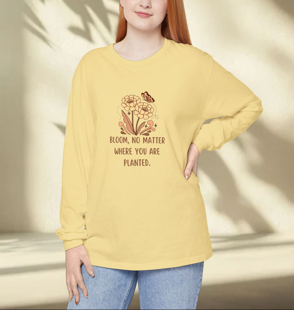 Person wearing a yellow long-sleeve shirt with a floral design and text, standing against a neutral background.