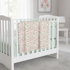 White crib with floral blanket in a nursery setting