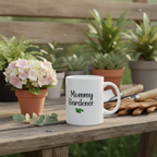 White mug with 'Mommy Gardener' text on a wooden table with plants in the background