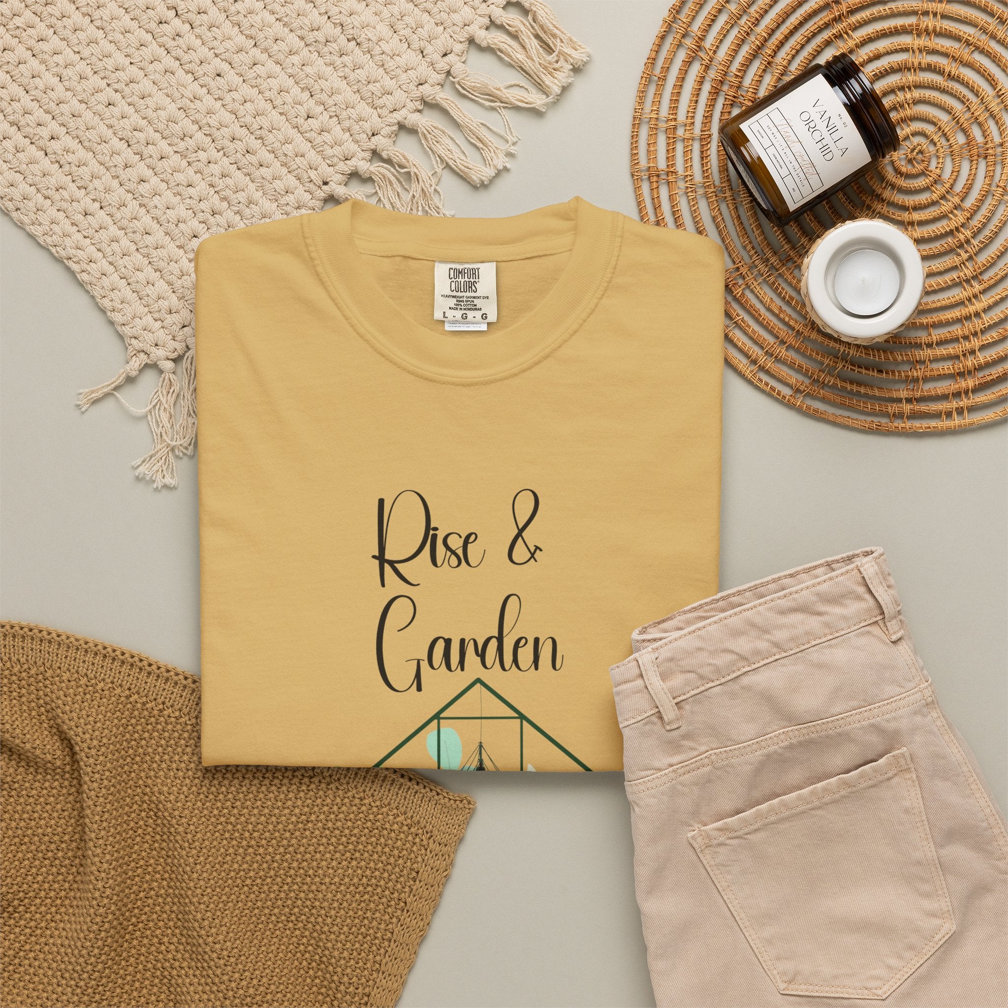Folded mustard yellow sweatshirt with 'Rise & Garden' text on a neutral background
