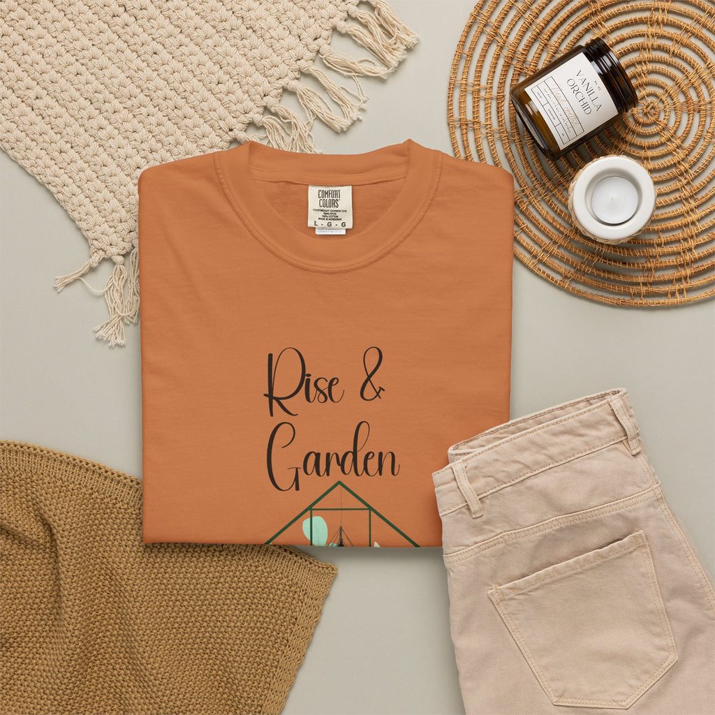 Folded brown t-shirt with 'Rise & Garden' text on a neutral background