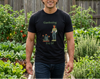 A man standing in a lush green garden wearing a black graphic t-shirt with a 'Gardening Try It!' design, paired with dark blue jeans.