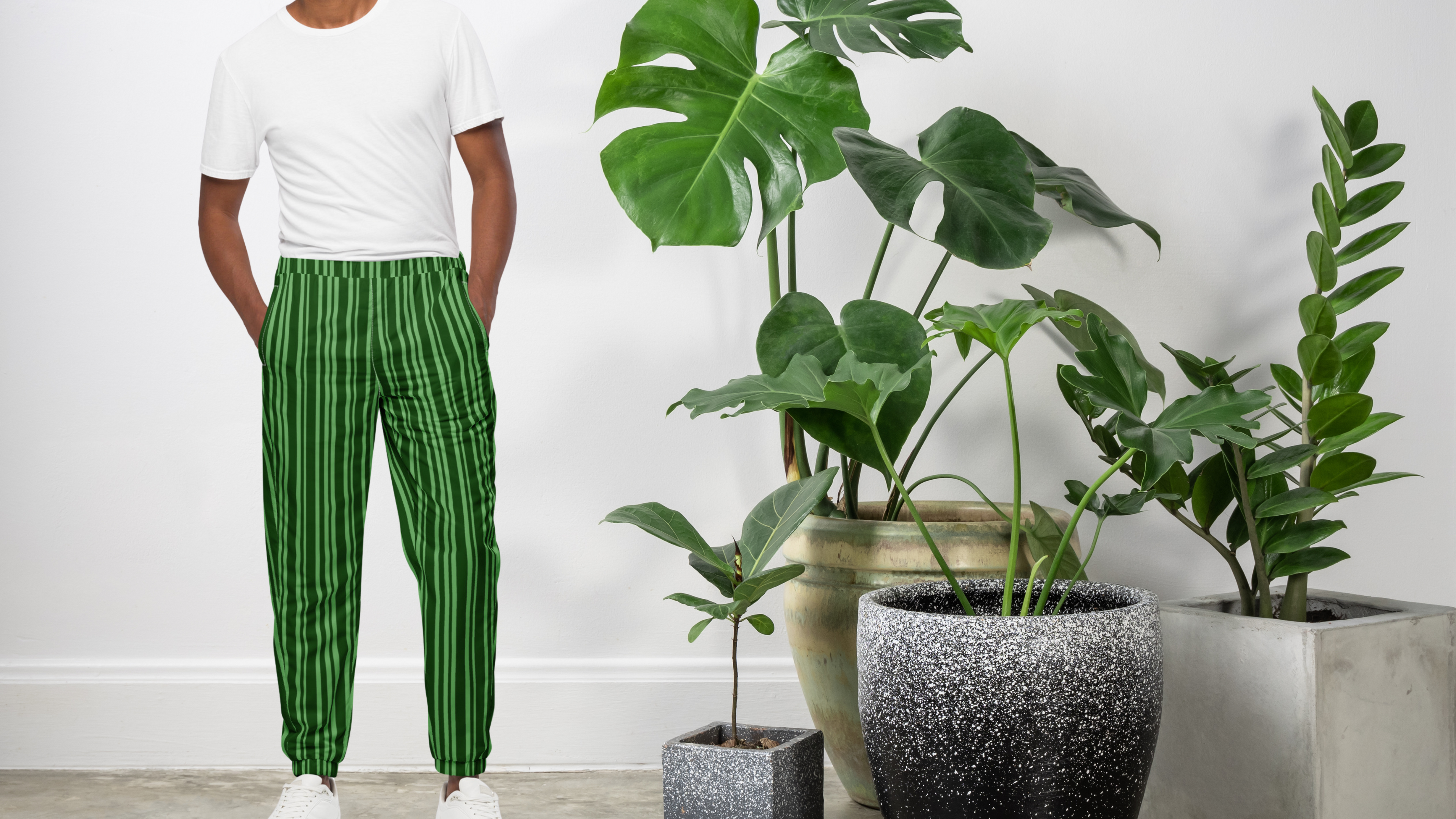 Person wearing green striped pants standing next to potted plants indoors.