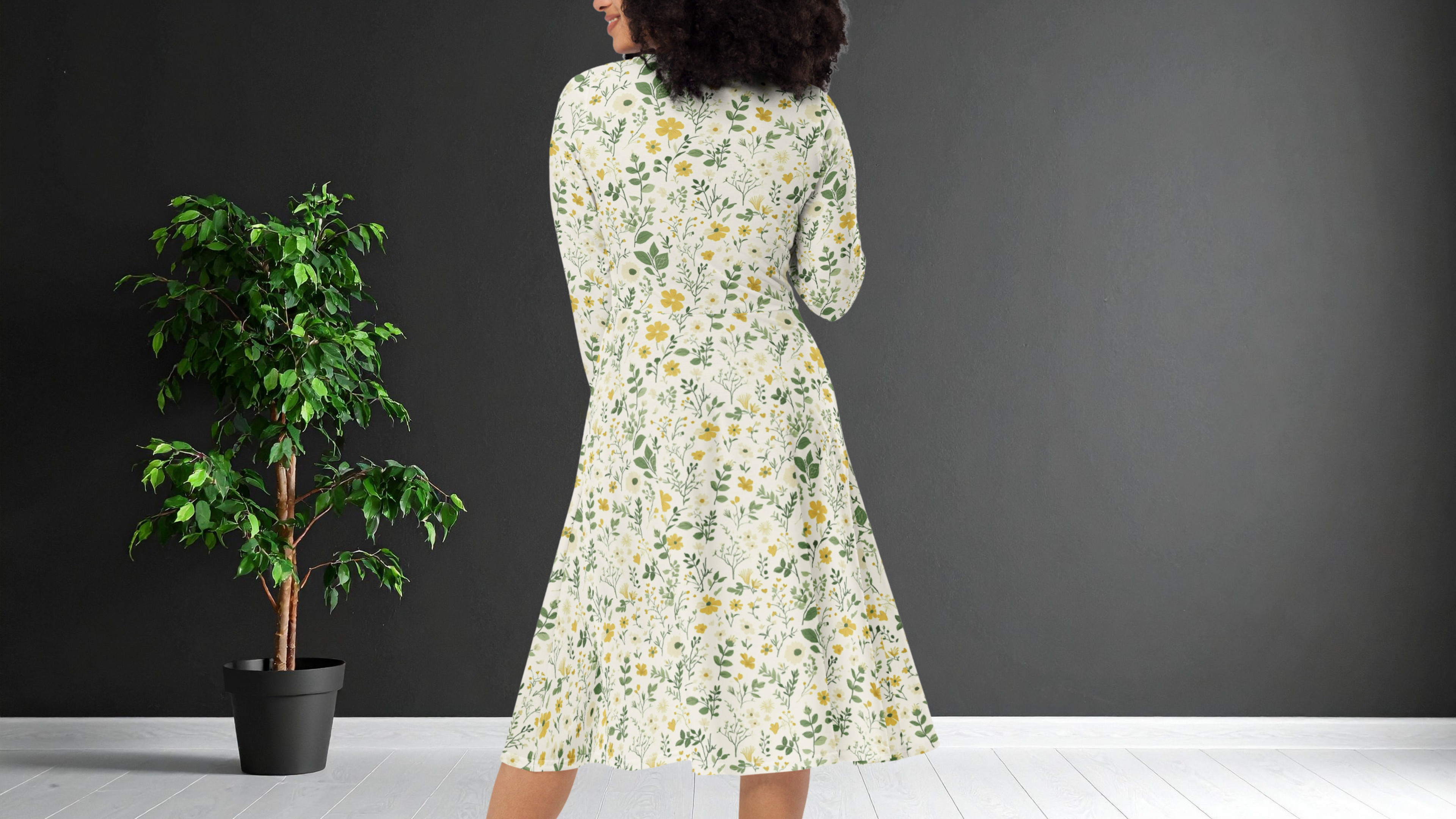 Woman wearing a floral dress standing next to a potted plant against a dark wall.