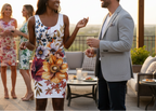 People socializing outdoors on a patio with floral dress and formal attire.