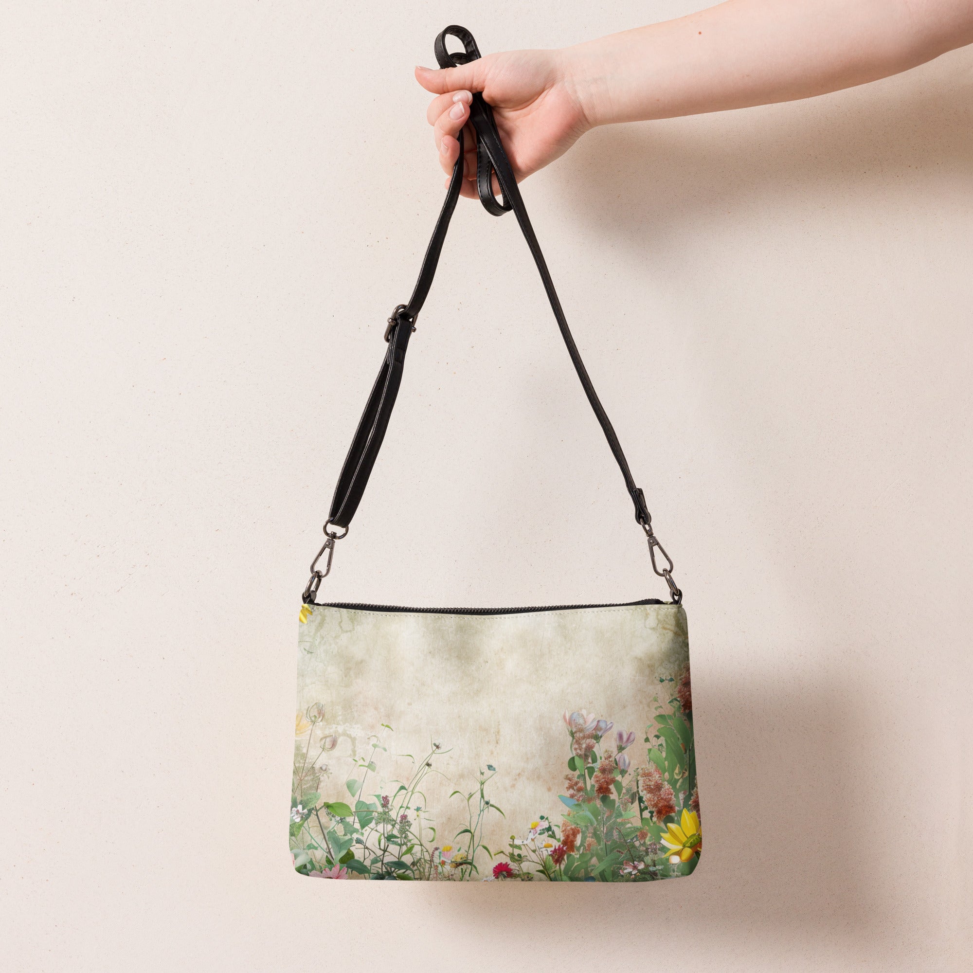 Handbag with floral pattern held by a hand against a plain background