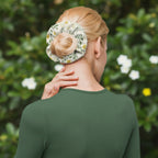 Woman using a floral hot water bottle on her neck against a white background