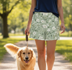 Person walking a dog in a park wearing floral shorts