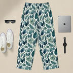 Leaf-patterned pants displayed with white sneakers, sunglasses, a tablet, and a watch on a beige background.