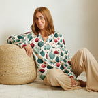 Woman wearing a patterned outfit sitting on the floor next to a woven ottoman.