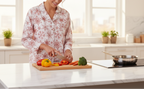 Woman cutting vegetables on a cutting board in a kitchen