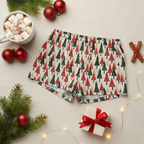 Holiday-themed boxer briefs with a red and green Christmas tree pattern, styled in a cozy flat-lay with a mug of marshmallow hot chocolate, red ornaments, pine branches, cinnamon sticks, and a small gift box.