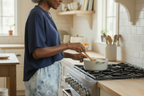 Woman cooking in a kitchen with a pot on the stove.