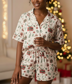 Woman wearing a Christmas-themed pajama set holding a mug in front of a decorated Christmas tree.