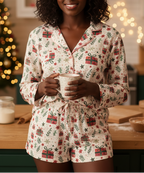 Person wearing a festive pajama set holding a mug in a kitchen with Christmas decorations.
