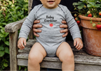 Baby boy in heather gray beside strawberry planters