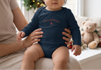 Baby girl in navy onesie by Christmas window