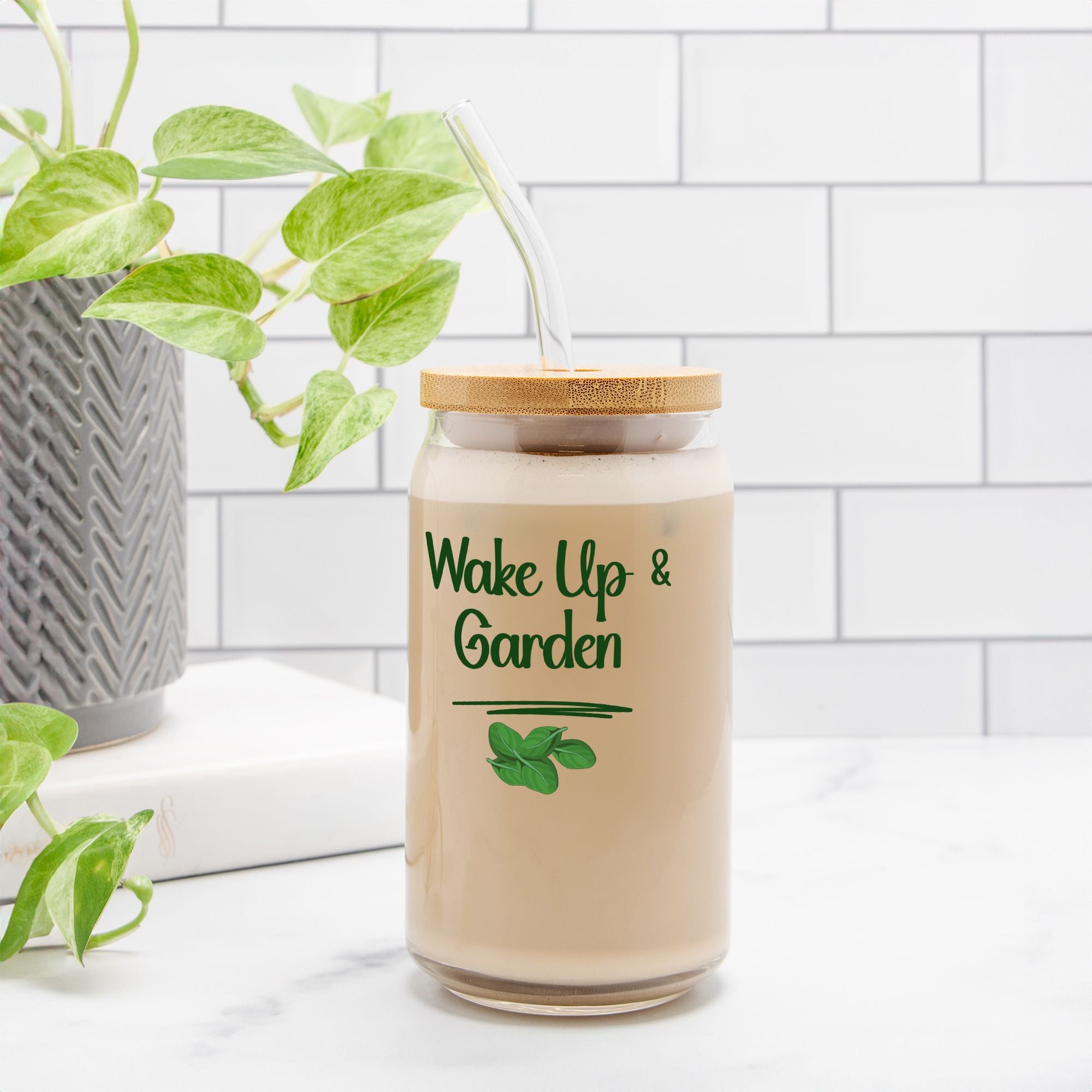 Glass jar with a wooden lid labeled 'Wake Up & Garden' on a white surface with a plant in the background.