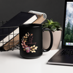 Black mug with floral design and text on a desk with laptop and books