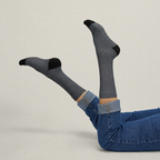 Person wearing fishnet socks with black accents and blue jeans on a light background