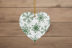 Heart-shaped ornament with green snowflake pattern on a wooden background