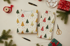 Folded Spring Christmas tree-print men’s pajama set with kraft gifts, ribbon, tags, scissors, and evergreen sprigs