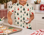 Child wearing a Christmas tree pajama top while decorating holiday cookies