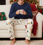 Blond man wearing Spring Christmas Tree pajama pants with a solid navy shirt in a Christmas living room