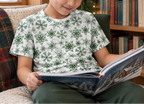 Child wearing green snowflake kids pajama top while reading a winter story
