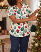 A woman decorating a Christmas tree wearing the ivory ornament-print short-sleeve pajama top and navy pajama pants.
