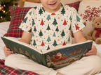 Child wearing a Christmas tree pajama top while reading in a festive bedroom