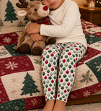 Child wearing Holiday ornament leggings cuddling a stuffed reindeer at bedtime