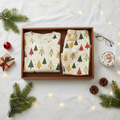 Folded Spring Christmas tree-print men’s pajama top and pocketless pants with cocoa, gifts, glasses, pinecones, greenery, and warm lights
