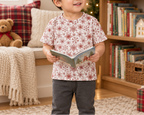 Toddler wearing Red Snowflake kids pajama top holding a winter storybook