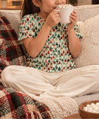 Girl in Leafy Dreams pajama top sipping hot cocoa on the sofa
