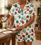 A woman writing holiday cards in the ivory ornament-print short-sleeve pajama top and matching pajama shorts.