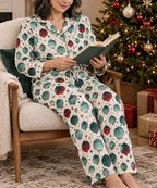 Woman in matching ornament print button down pajamas reading by a Christmas tree
