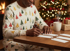 Older Black man wearing Spring Christmas pajamas while writing gift tags