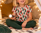 Child in Christmas Tree kids pajama top in a blanket fort with fairy lights
