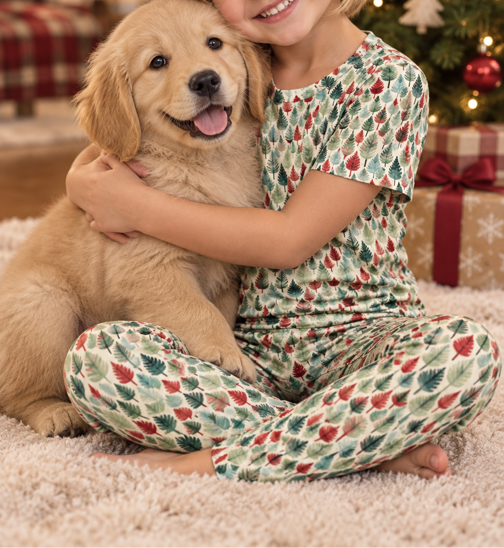Girl in Leafy Dreams pajamas hugging a puppy by the Christmas tree
