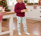 Child wearing Green Snowflake kids leggings carrying holiday cookies in a festive kitchen