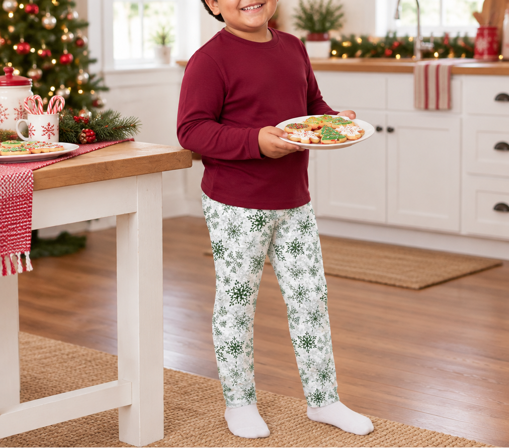 Child wearing Green Snowflake kids leggings carrying holiday cookies in a festive kitchen