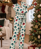 Woman wearing matching ornament print button down pajamas while decorating a Christmas tree