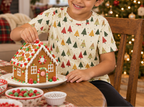 Child wearing Spring Christmas kids pajama top while decorating a gingerbread house