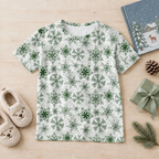 Green snowflake kids pajama top flat lay with slippers, storybook, pinecone and wrapped gift