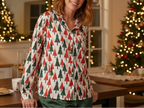 White woman wearing a Christmas tree pajama top with navy pants in a holiday kitchen and dining area