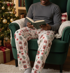 Mixed race man wearing Christmas Present men’s pajama pants with a solid charcoal shirt in a reading nook