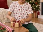 Child wearing Red Snowflake kids pajama top while wrapping a holiday gift
