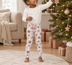 Toddler wearing Red Snowflake kid pajama leggings decorating a Christmas tree